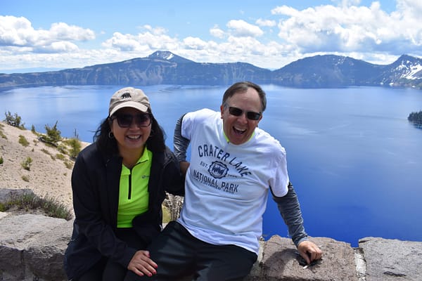 Two cyclists laughing on the edge of Crater Lake